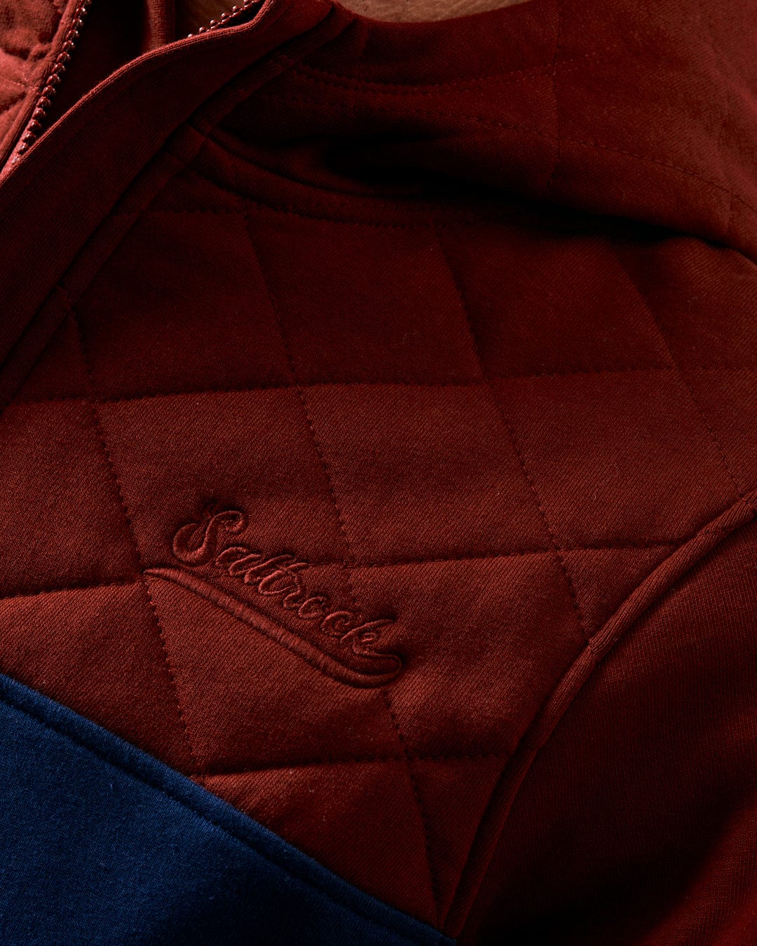 Close-up of a person wearing the "Aiken - Mens 1/4 Neck Recycled Hoodie" in red with an embroidered "Saltrock" logo on the chest, showcasing Saltrock branding and crafted from recycled materials.