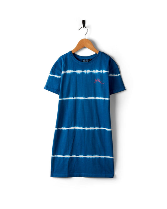 A blue tie-dye Aubrey - Kids T-Shirt Dress - Blue with white horizontal stripes, short sleeves, and a small pink Saltrock branding logo on the chest, hanging on a wooden hanger against a white background. Made from 100% cotton for ultimate comfort.