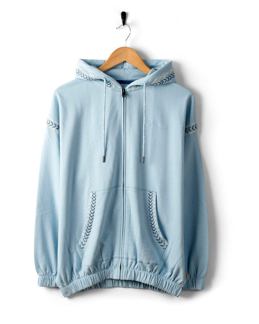 Light blue Auden - Womens Oversized Zip Hoodie - Blue with a drawstring hood and Grecian-styled stitching on the sleeves and hood, hanging on a wooden hanger by Saltrock.