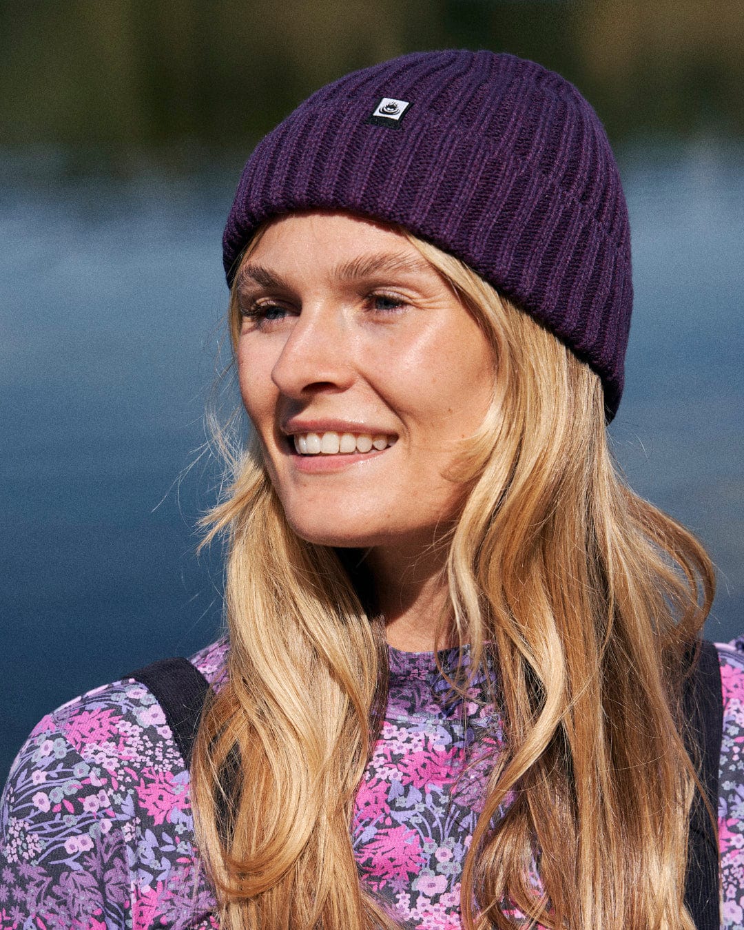 A woman wearing a Saltrock Maine - Fisherman Beanie - Dark Purple to keep warm by the water.