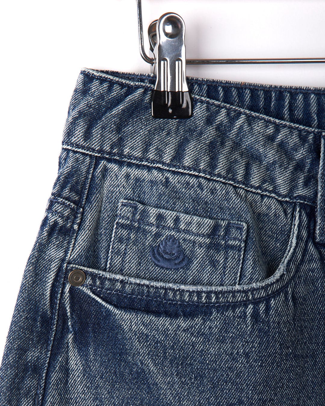 Close-up of the Brittany Women's High Waisted Denim Shorts in blue by Saltrock, featuring a distressed denim finish. The image focuses on the front pocket area, showcasing the texture and detailing of the fabric.