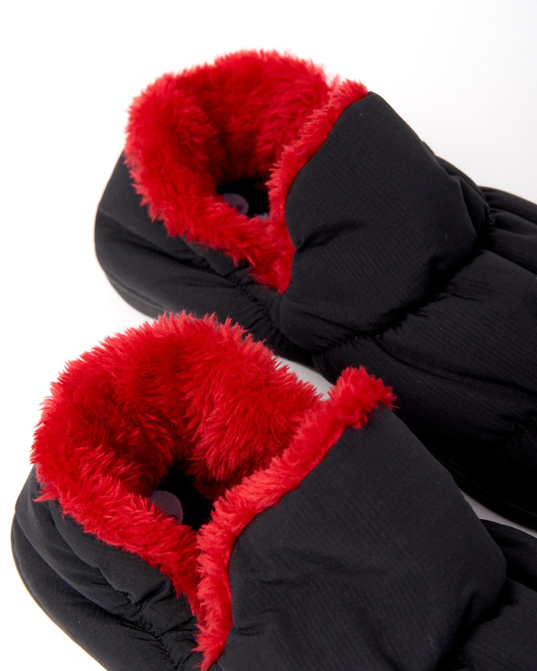 A close-up of Saltrock's Camping Slipper in black, featuring a vibrant red fuzzy interior and a grippy sole, set against a white background.