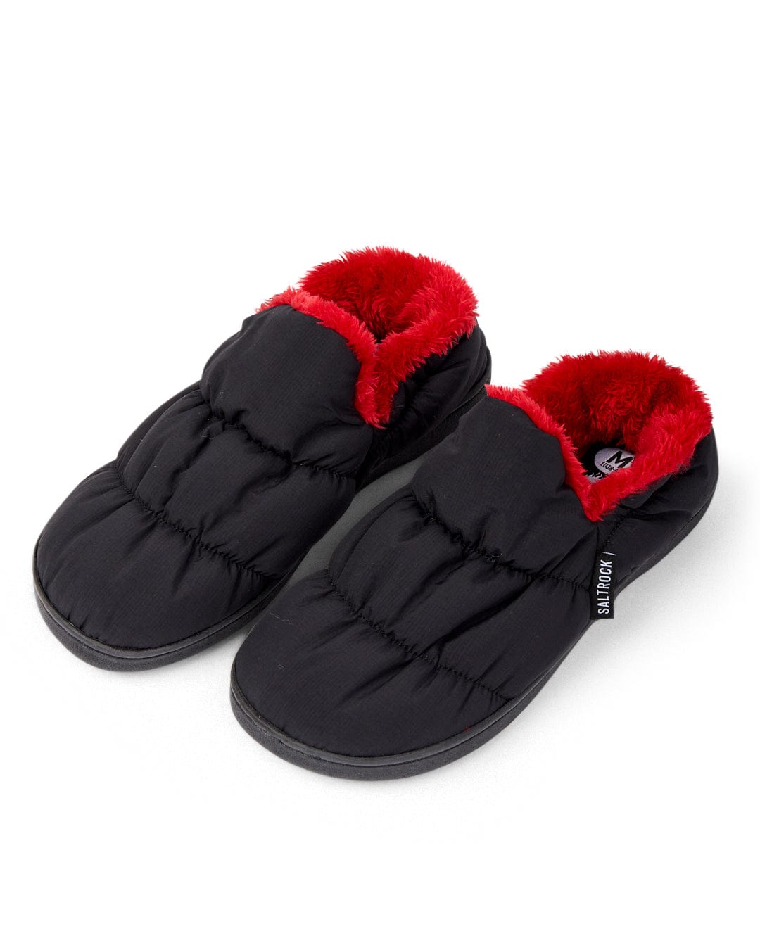 A pair of sleek Camping Slipper - Black from Saltrock, boasting a soft borg lining and a red plush interior, with a grippy sole that ensures added stability on a white background.