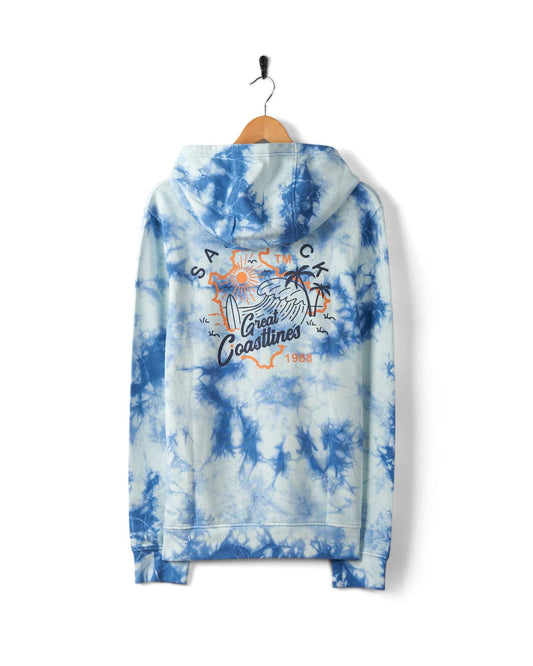 A Coastline - Mens Tie Dye Pop Hoodie - Blue hangs on a wooden hanger. Crafted from 100% cotton, the back showcases a graphic beach scene with the words "Great Coastlines," "Sat & Tck," and "1988," adorned with subtle Saltrock branding.