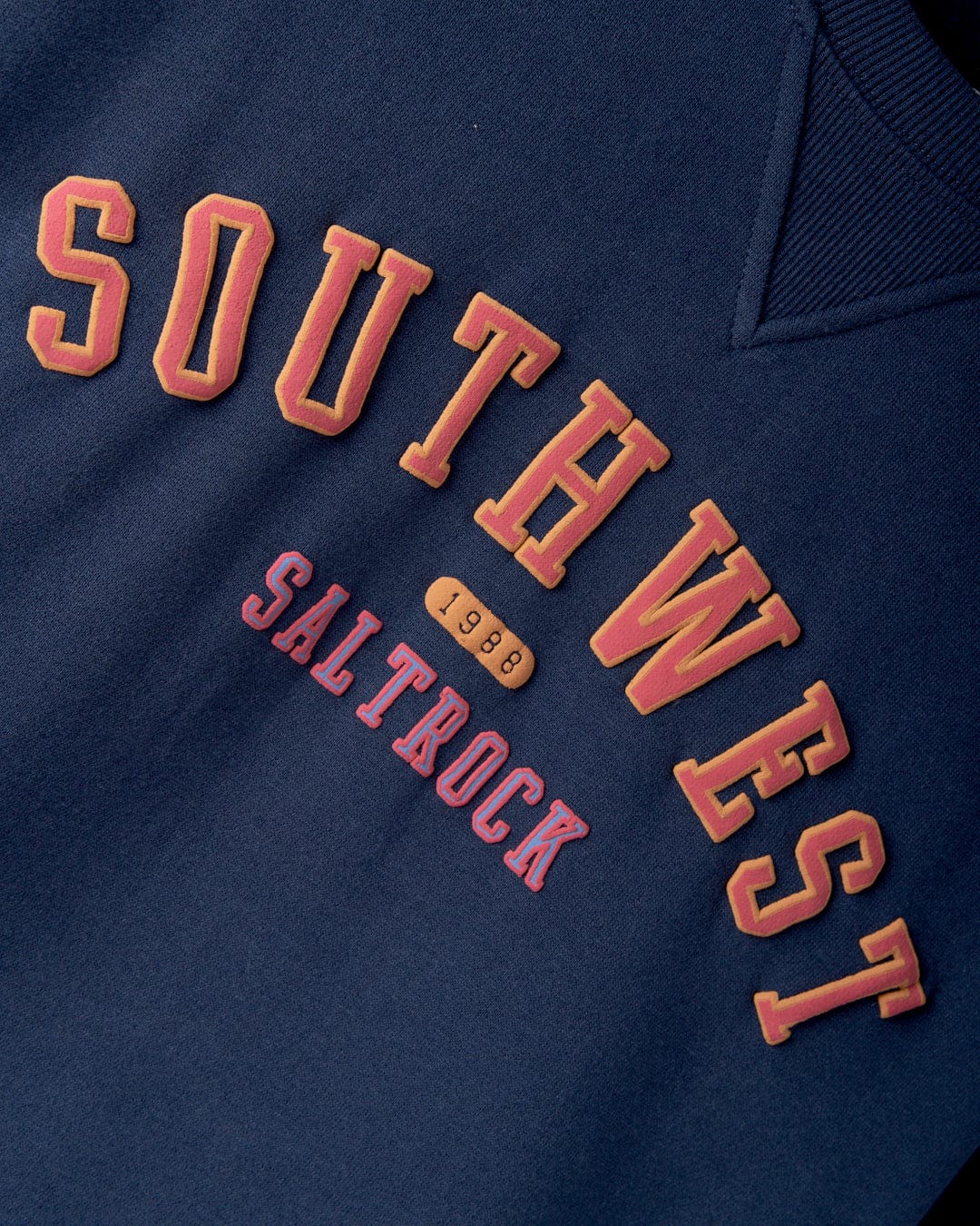 Close-up of the **Saltrock College Women's Oversized Sweat - Blue** displaying the text "SOUTHWEST SALTROCK" with a small "Southwest 1988" emblem in between the words and subtle retro stripes detailing.