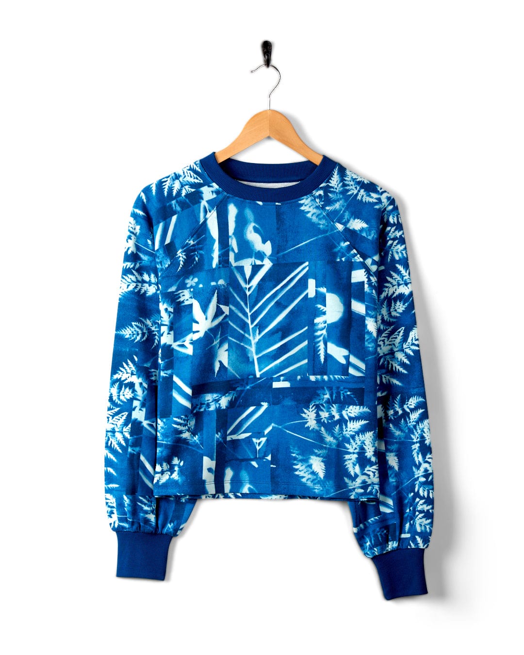 A Cyanotype - Womens Recycled Boxy Sweat - Blue by Saltrock with a white abstract forest print, hanging on a wooden hanger against a plain white background. Made from recycled materials, this piece features a boxy fit for added comfort and style.