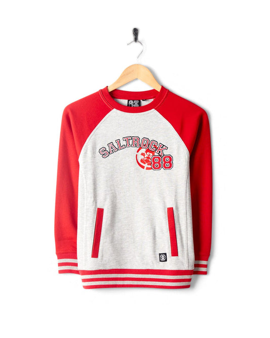 A Drop Out - Kids Sweat Shirt - Grey/Red featuring bold Saltrock branding and the number "88" on the front, complete with striking red raglan sleeves, displayed on a wooden hanger against a white background.