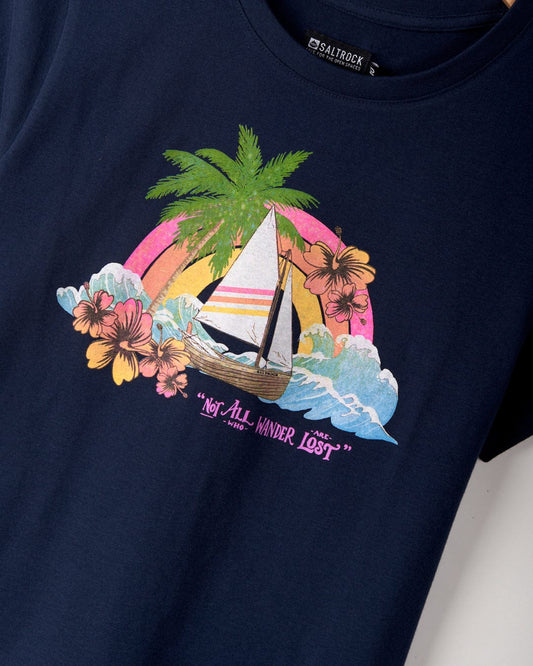 Close-up of a Saltrock Floral Lost Ships - Womens T-Shirt - Blue featuring a tropical scene with a sailing boat, palm tree, hibiscus flowers, and waves, accompanied by the text "Not All Who Wander Are Lost." This 100% cotton tee is machine washable for easy care.