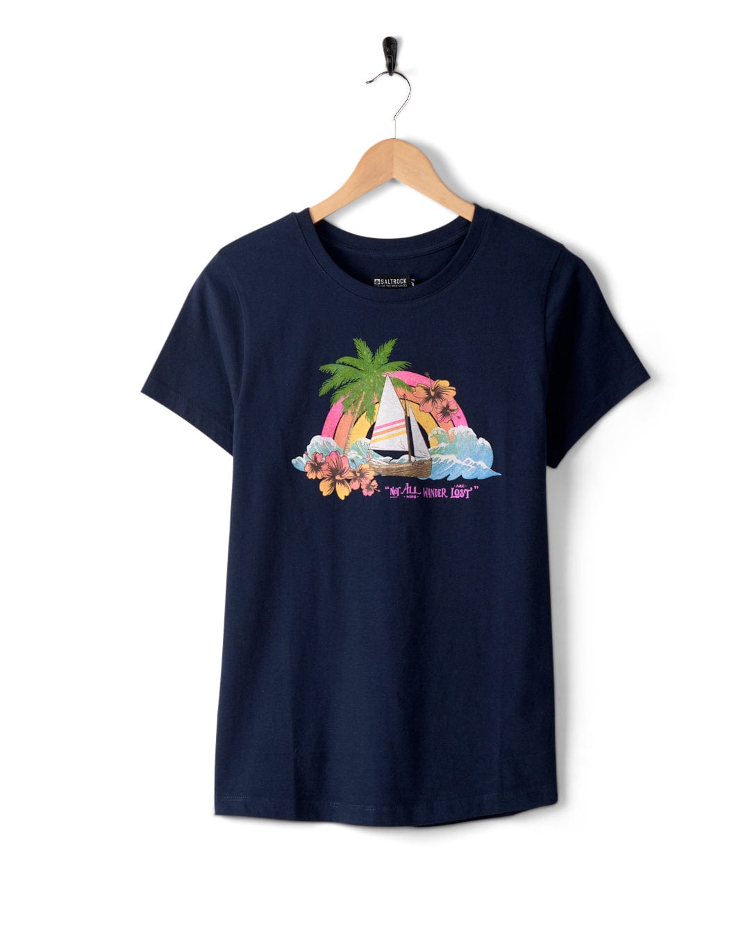 A navy blue Floral Lost Ships - Womens T-Shirt - Blue featuring the Saltrock graphic with a sailboat, palm trees, and flowers. The text "All waves lead" is displayed on a wooden hanger against a white background. Made from 100% cotton and machine washable for easy care.