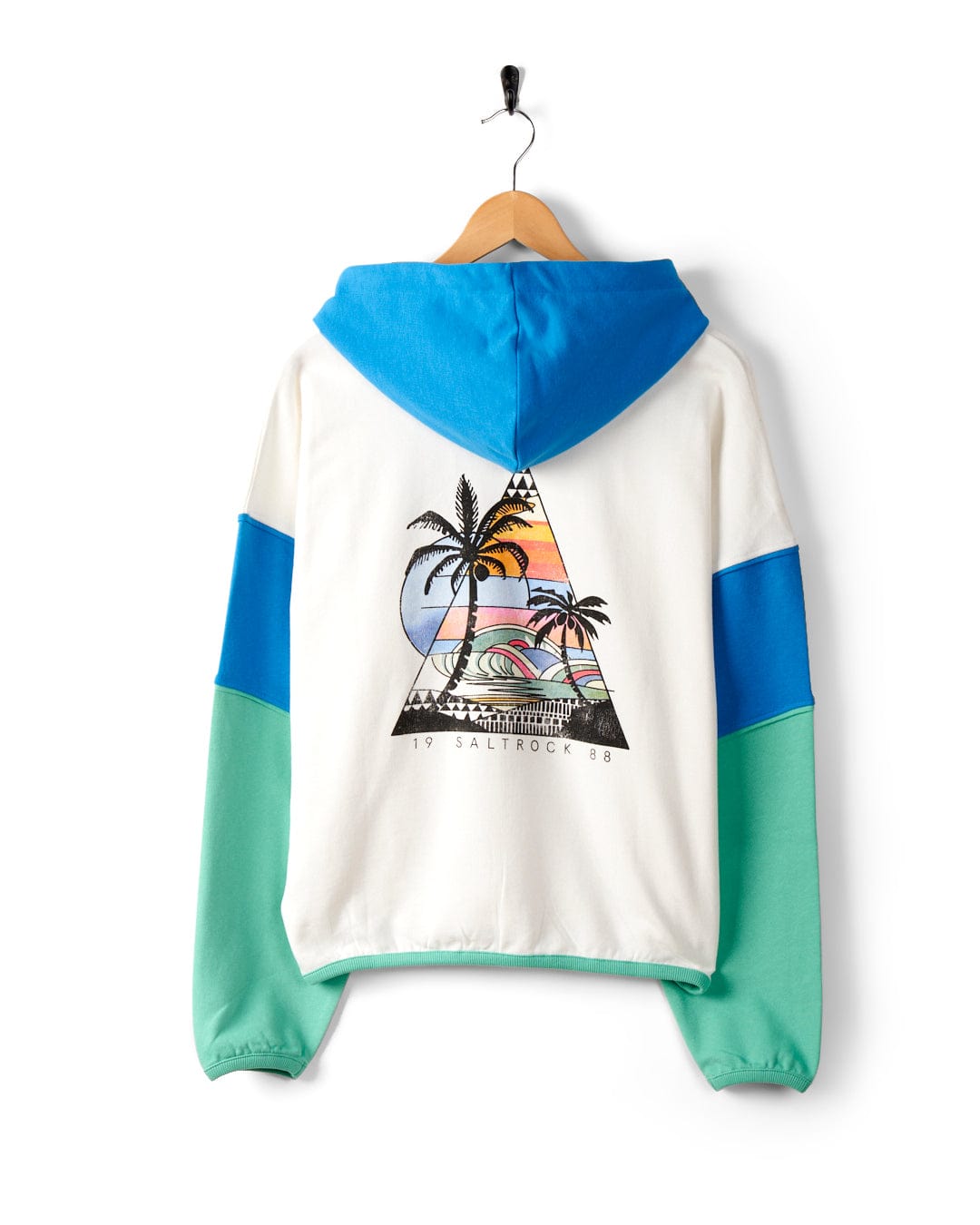 A white hoodie on a hanger, featuring a back design of Palm Beach graphics with palm trees, a sunset, and waves. The text "19 SAILROCK 88" is displayed beneath the graphic. Crafted from 100% cotton, it also features Saltrock branding for an authentic touch. This is the Geo Beach - Womens Pop Hoodie - White by Saltrock.