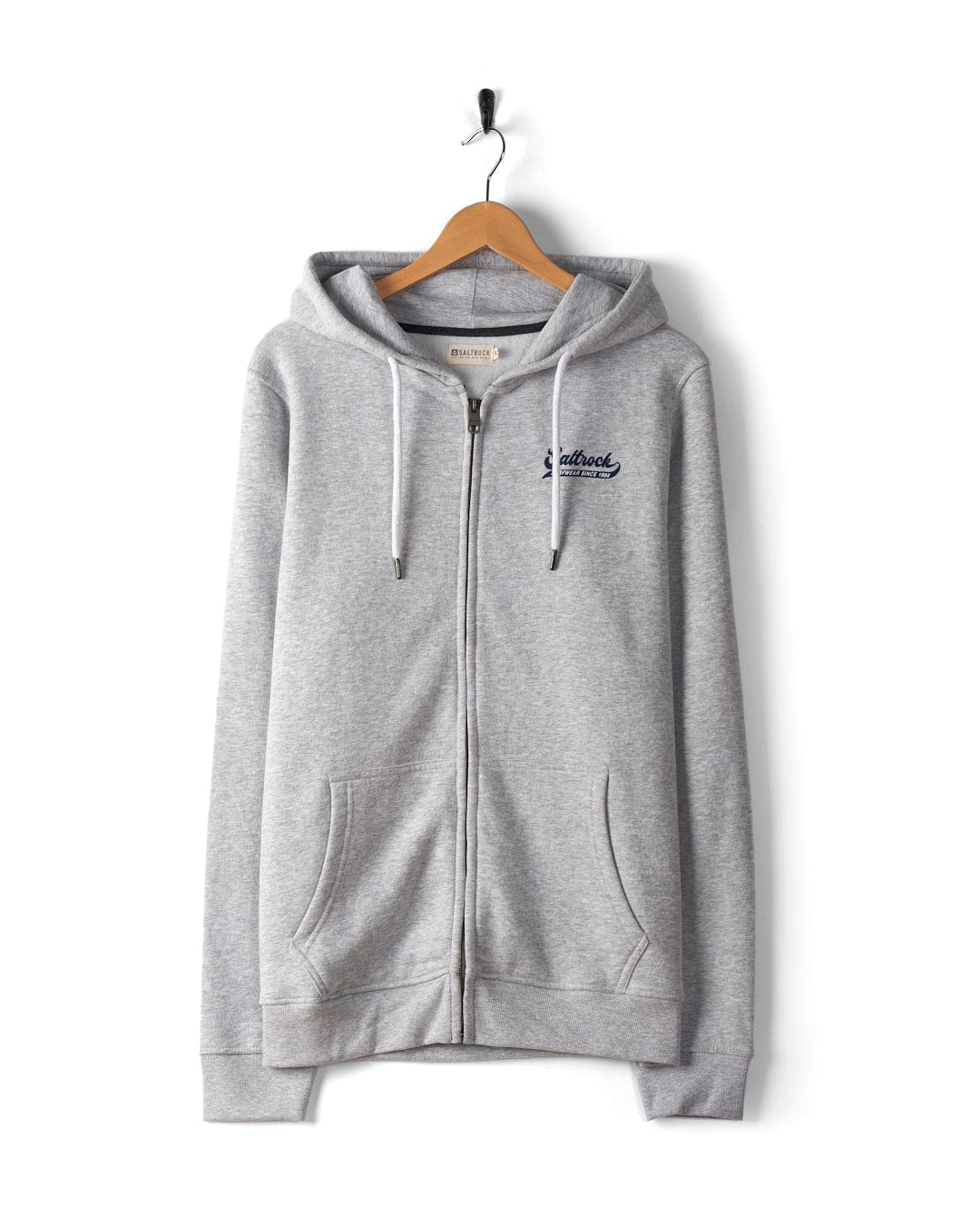 A Home Run - Mens Zip Hoodie - Grey with Saltrock branding on the left chest hangs on a wooden hanger, suspended by a metal hook against a white background. Featuring a hood with drawstrings, this stylish piece is machine washable for easy care.