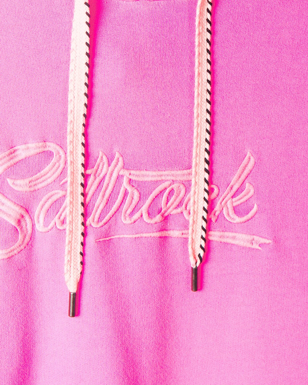 Close-up of a Saltrock branded Instow - Womens Pop Hoodie - Pink with white drawstrings and cursive embroidered text that reads "Saltrock." Made from 100% cotton for ultimate comfort.