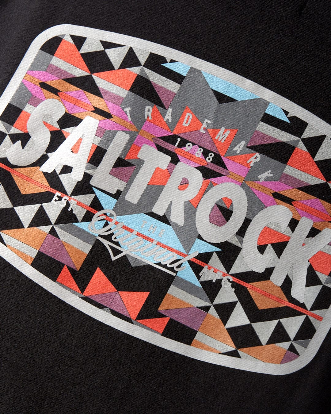 A close-up of the Jungle Wilds 2 - Mens T-Shirt in black by Saltrock, featuring a colorful geometric design and the text "Saltrock Trademark 1988, Est The Original Inc." printed on it. Made from 100% cotton for ultimate comfort.