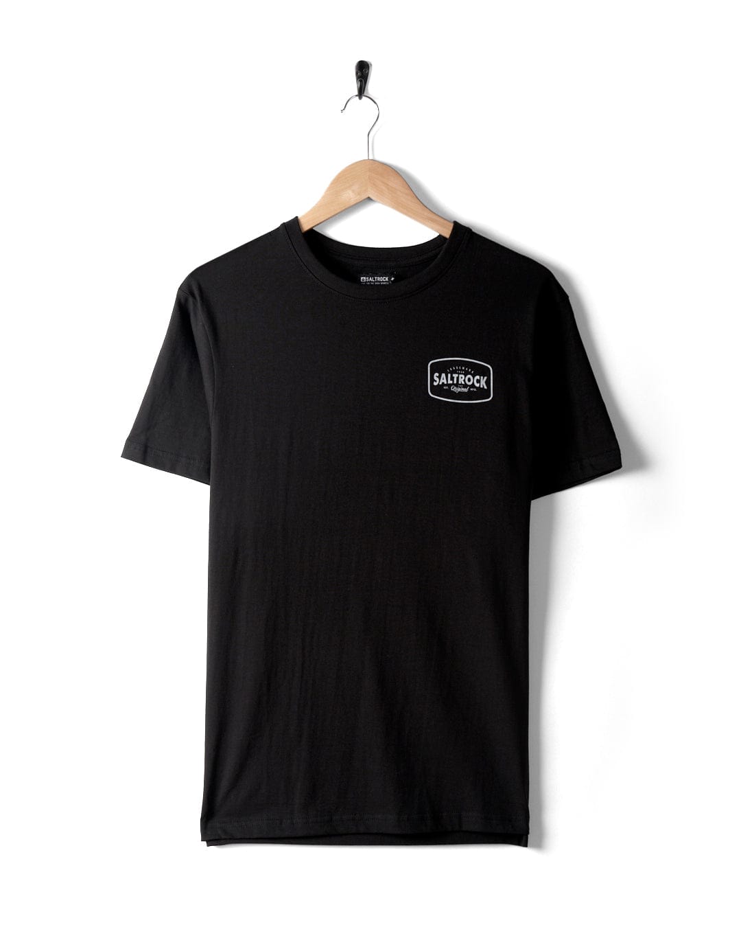 A plain black t-shirt, named "Jungle Wilds 2 - Mens T-Shirt," made of 100% cotton with a small "Saltrock" logo on the left chest area, hanging on a wooden hanger attached to a hook against a white background.