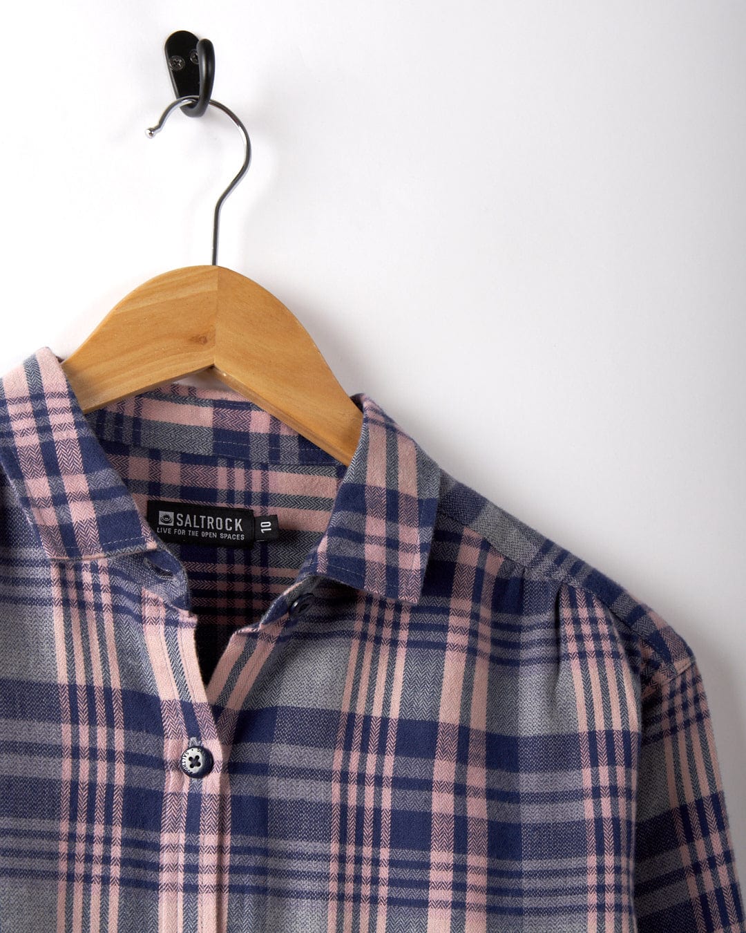 Kizzie - Women's Longline Shirt in a purple check print by Saltrock, displayed on a wooden hanger against a white wall.