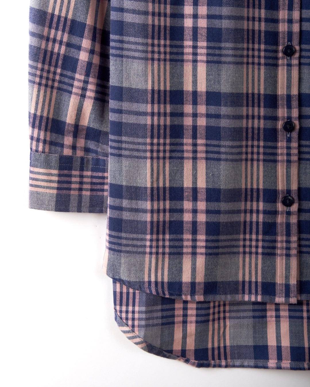 A close-up of the Saltrock Kizzie women's longline shirt in a purple check print highlights the lower half with buttons, cuffs, and a curved hem, crafted from 100% cotton for ultimate comfort.