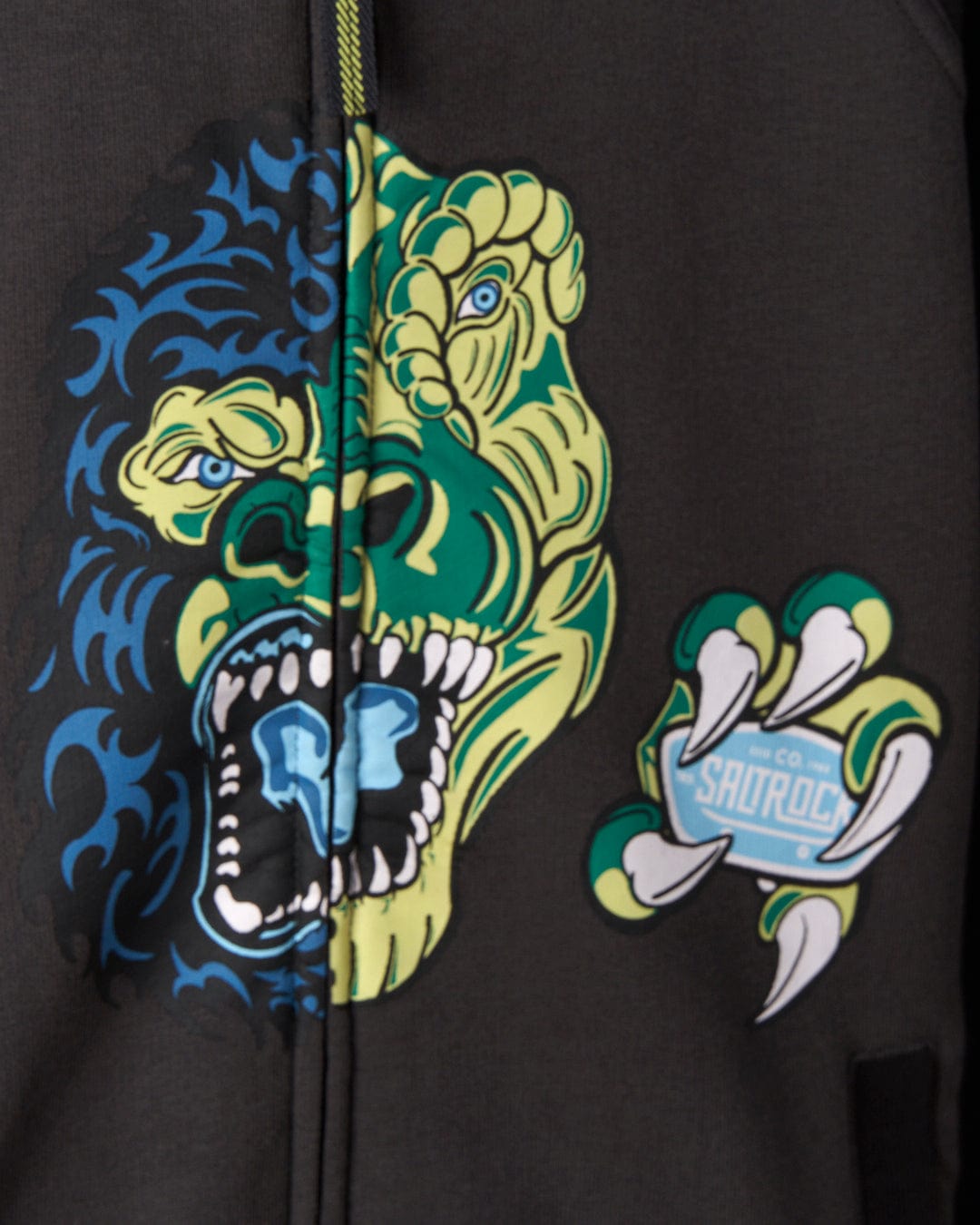 A close-up image of a Las Vegas Smackdown - Recycled Oversized Kids Zip Hoodie - Black by Saltrock featuring an artistic design of a half-blue, half-green roaring gorilla's head and a claw holding a badge with text that reads "Saltrock." The glowing graphics are made from recycled materials, adding an eco-friendly touch.