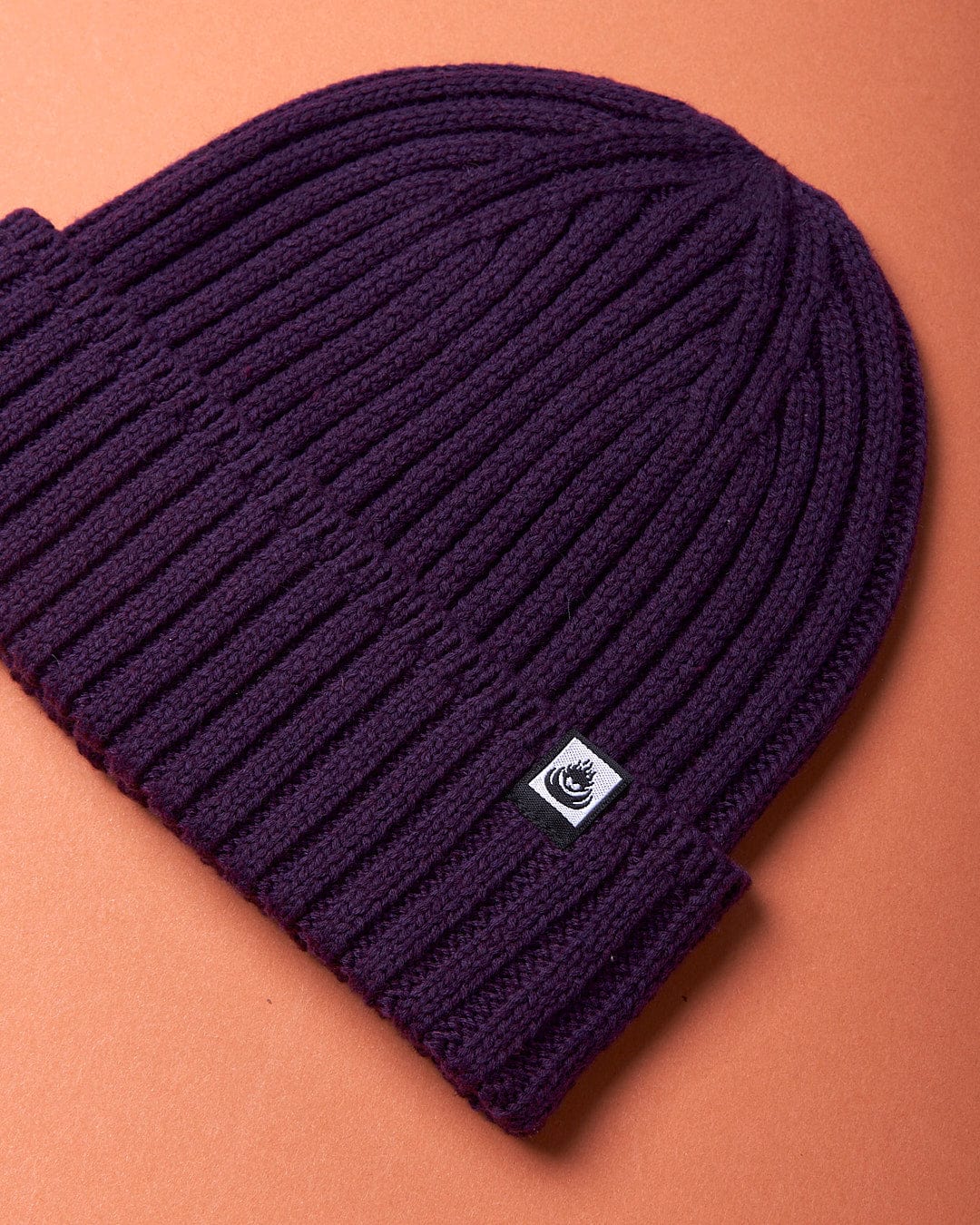 A Maine - Fisherman Beanie - Dark Purple by Saltrock on an orange background.