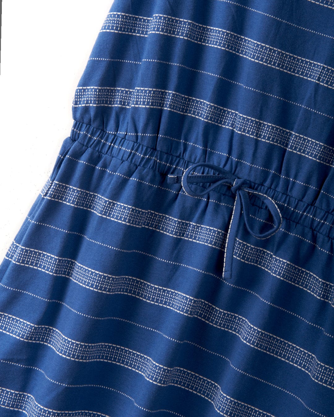 Close-up of a knee-length blue dress with white horizontal stripes, featuring an elasticated waist and a tied drawstring for a snug fit. Crafted from 100% cotton for ultimate comfort, the Marina Bauhaus - Womens Dress - Blue by Saltrock is perfect for both casual outings and everyday wear.
