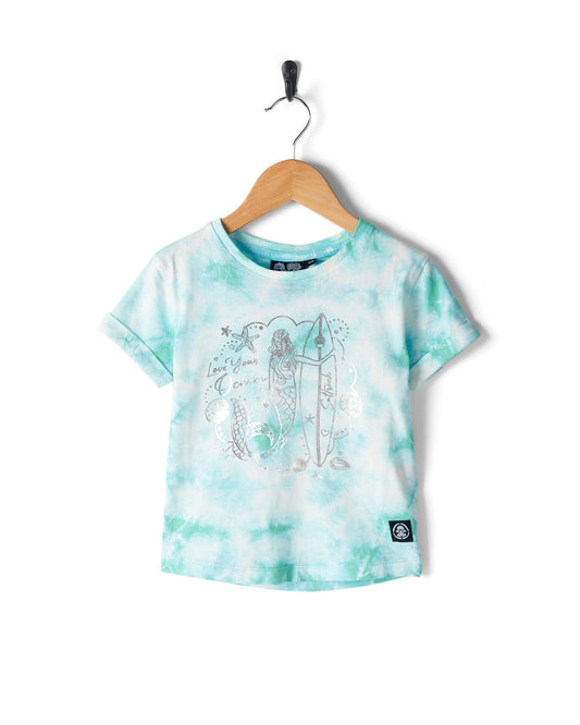A blue and white tie-dye Saltrock Mermaid Surf - Kids T-Shirt - Turquoise/White on a hanger featuring a 100% cotton fabric with a mermaid print holding a surfboard and the text "Love you, Ocean.