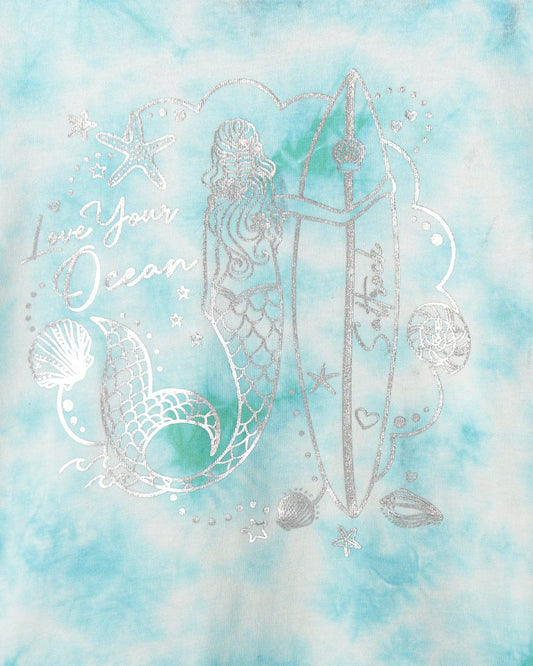 Illustration of a mermaid with a surfboard surrounded by ocean-themed elements, including shells and starfish, on a tie-dye blue background. The text "Love Your Ocean" completes this vibrant mermaid print design, perfect for Saltrock Mermaid Surf - Kids T-Shirt - Turquoise/White.