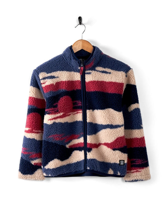 The "Mountain Trail - Kids Recycled Borg Zip Fleece - Blue" from Saltrock features an abstract pattern in red, beige, and blue that evokes a mountain landscape. Displayed on a wooden hanger against a white backdrop, this fleece offers warmth with its recycled cozy sherpa fabric and guarantees ultimate comfort with its sherpa-lined collar.