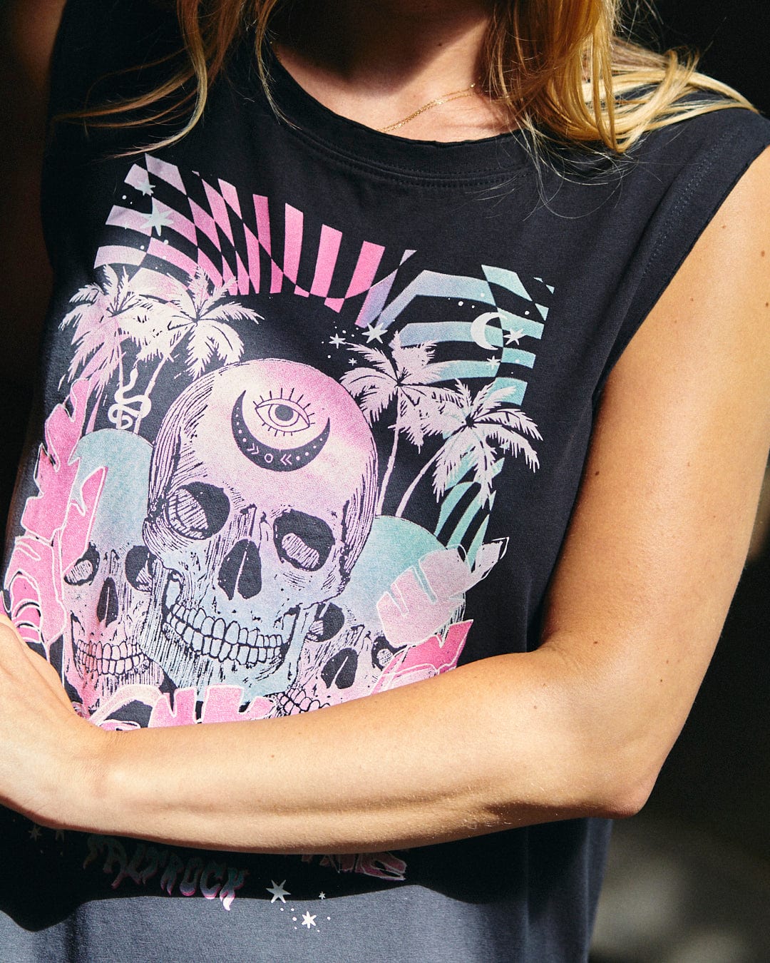 A person wearing the Mystic Skulls - Women's Jersey Vest Midi Dress in black, made from 100% cotton, featuring a colorful neon warped skull illustration, palm trees, and geometric patterns along with subtle Saltrock branding.