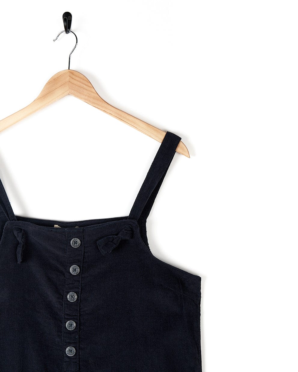 A Nancy - Womens Cord Jumpsuit - Dark Blue by Saltrock with buttons down the front, hanging on a wooden hanger against a white background—perfect for the fashion-conscious woman.