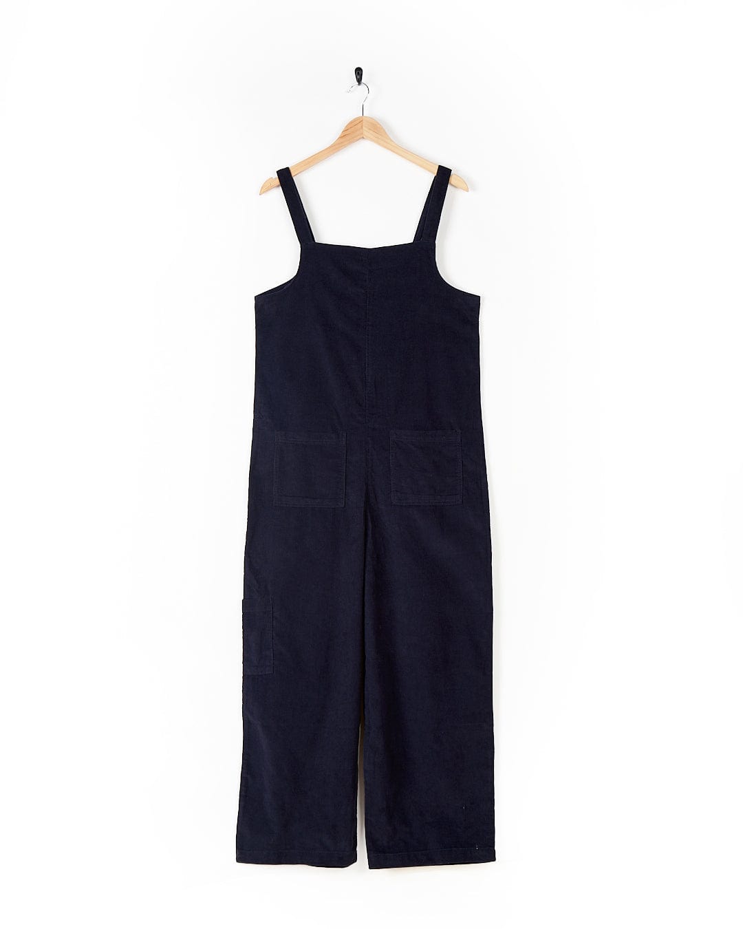 A Nancy - Womens Cord Jumpsuit - Dark Blue from Saltrock displayed on a wooden hanger against a white background, perfect for the fashion-conscious woman.