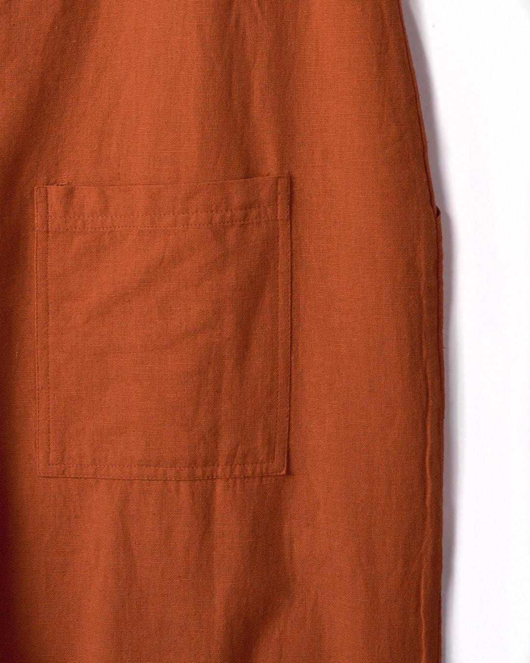 A close-up of an orange fabric with a square patch pocket sewn onto it, made from a comfortable cotton linen material, Nancy - Womens Jumpsuit - Brown by Saltrock.