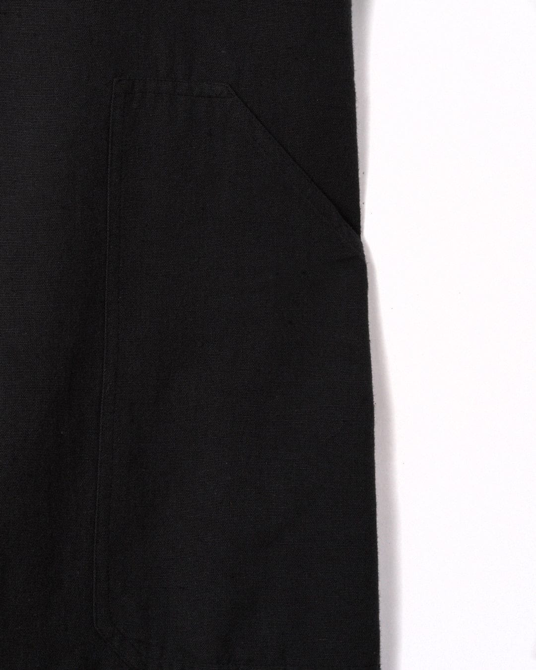 Close-up view of a black cotton fabric with a stitched pocket on the left side. The background is white. This fabric is from the Nancy - Womens Dungarees - Dark Grey by Saltrock.