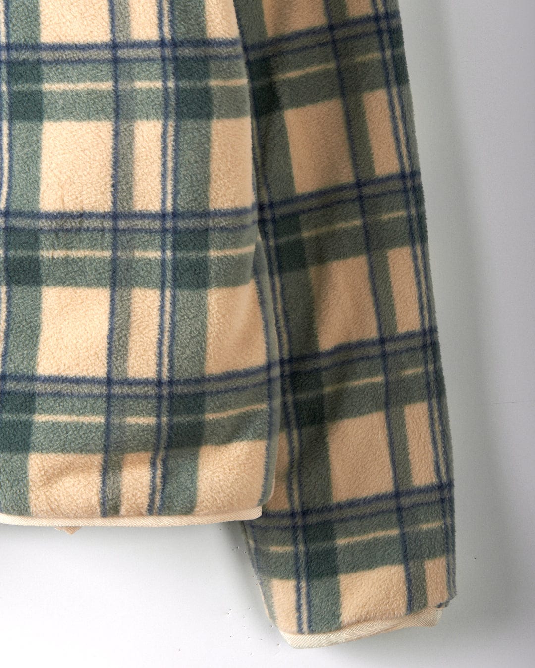 Close-up of a sleeve from the Saltrock Piper Women's Reversible Zip Collarless Fleece in cream, made from recycled materials, set against a light background.