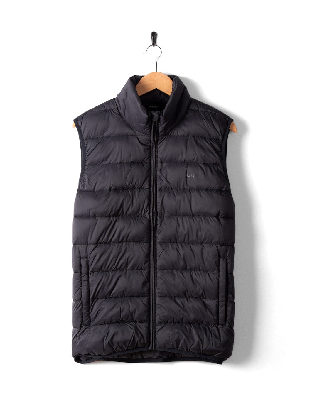 The Saltrock Resin Gilet, a dark grey men's sleeveless puffer vest with a front zipper, crafted from recycled materials, is displayed on a wooden hanger against a white background.