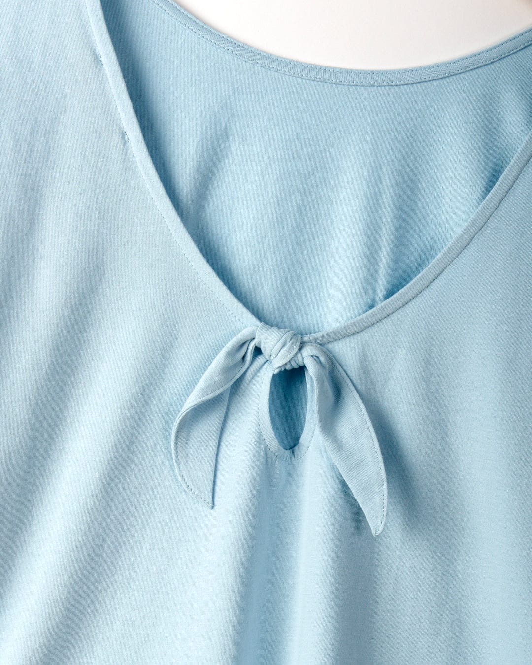 Close-up of a light blue garment made from 100% cotton with a V-shaped neckline featuring a small knot and keyhole detail at the center. The product is the Rhoda - Womens T-Shirt - Light Blue by Saltrock.