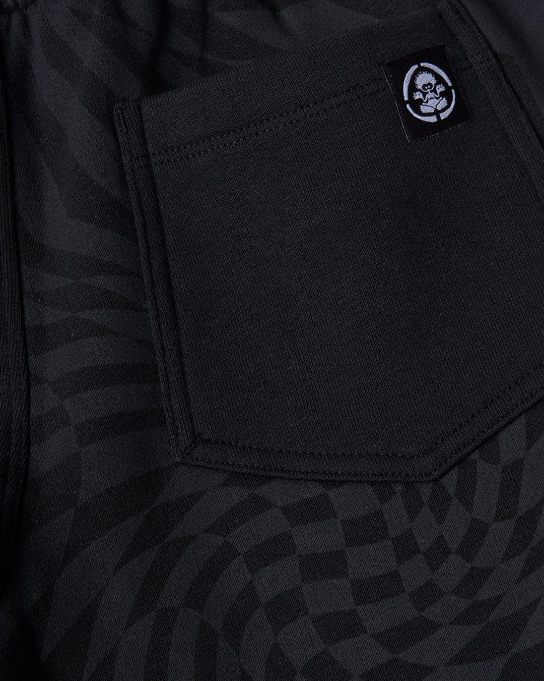 A black pocket with a geometric print on the Rip It - Kids Sweatshort - Black by Saltrock.