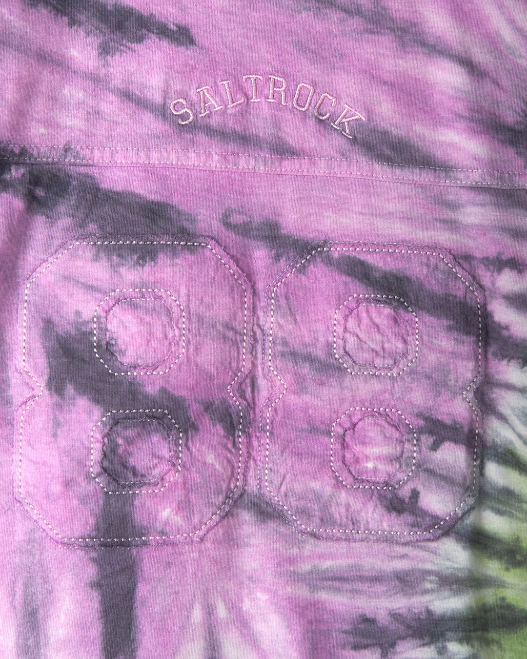Close-up of a purple and black tie-dye print fabric with the number "88" stitched in bold white thread and the word "SALTROCK" embroidered above it, showcasing classic Saltrock branding. The material is 100% cotton for a comfortable feel. This is the Rock Valley - Kids T-Shirt - Multi by Saltrock.