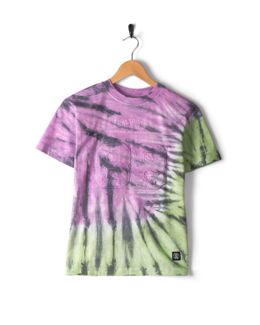 Rock Valley - Kids T-Shirt - Multi in green and purple, hanging on a wooden hanger with a black hook. Crafted from 100% cotton, the shirt features a small patch on the lower right side and subtle Saltrock branding.