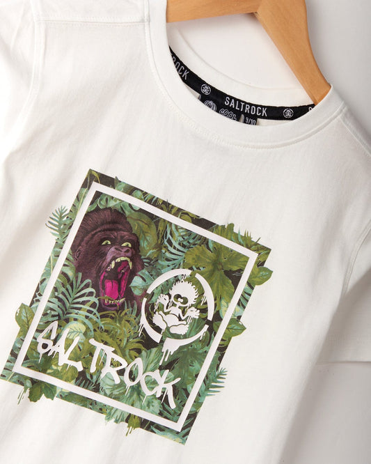 Rumble - Kids T-Shirt - White with a graphic design featuring a roaring gorilla surrounded by tropical leaves and bold "Saltrock" branding. Made from 100% cotton and machine washable, this t-shirt is hanging on a wooden hanger, ready to add some wild flair to your wardrobe.