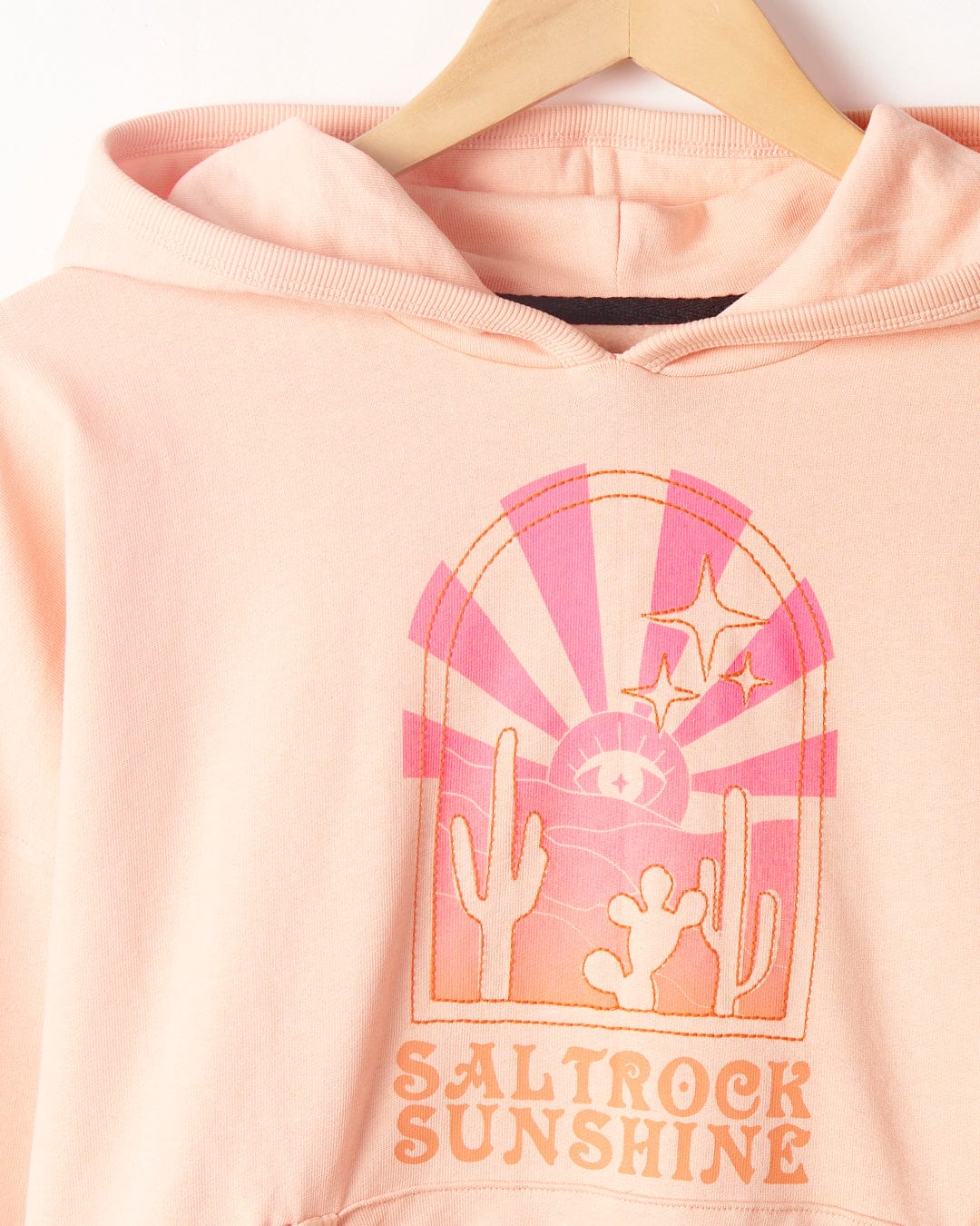 Saltrock Sunshine - Womens Pop Hood - Peach on hanger with a mystical ombre print showcasing cacti, sun rays, and stars inside an arch, captioned "Saltrock".