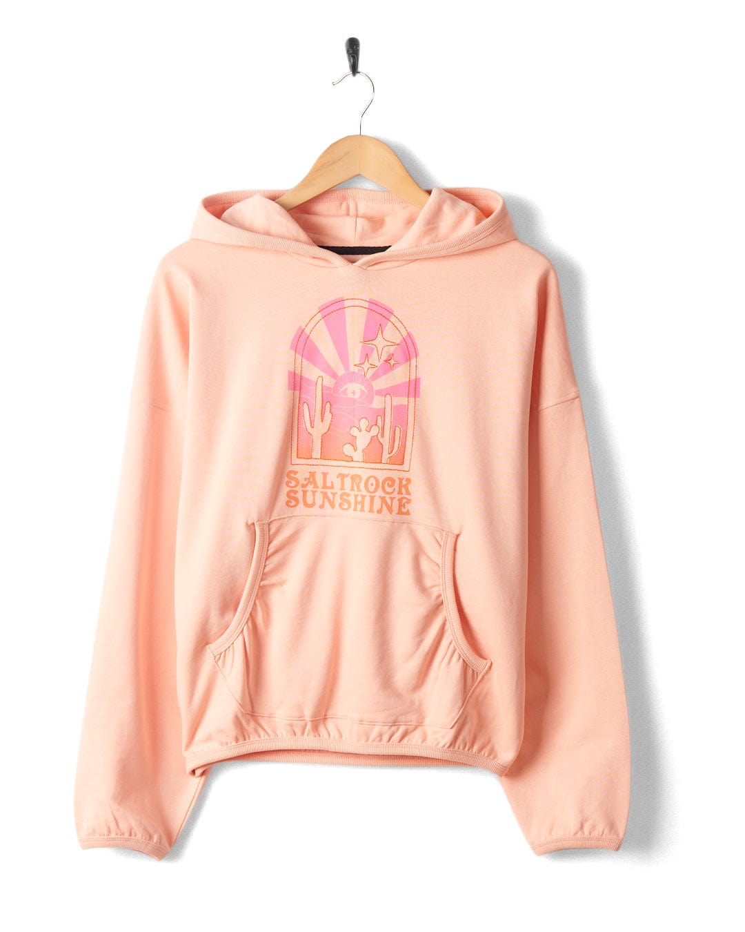 Light pink hoodie with a front pocket, showcasing a graphic design of a desert scene with cacti and a sun, under the text "Saltrock Sunshine". The Saltrock Sunshine - Womens Pop Hood - Peach from Saltrock is made from 100% cotton for ultimate comfort.