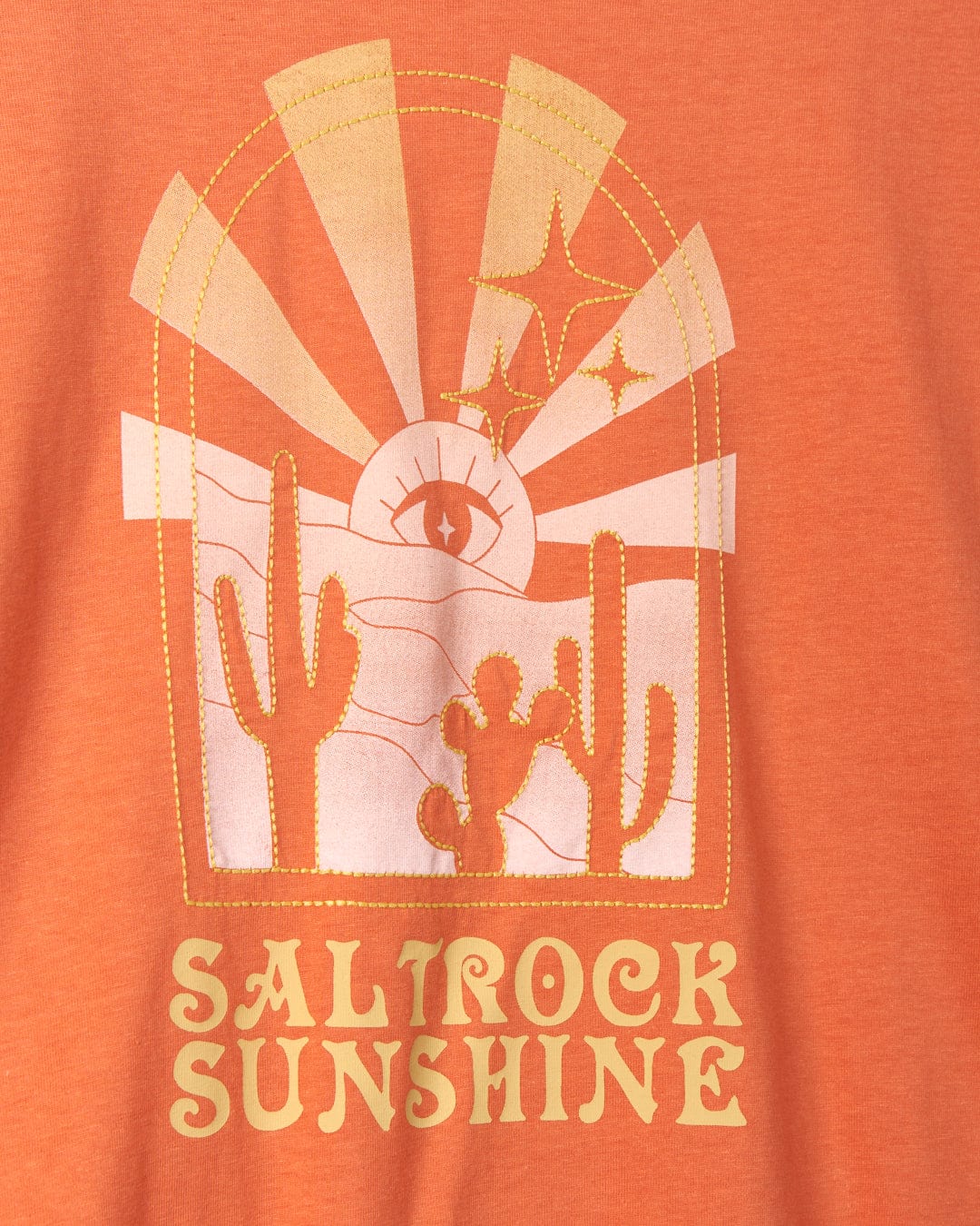 An orange graphic T-shirt featuring a mystic desert sunset design with cacti, stars, and the text 