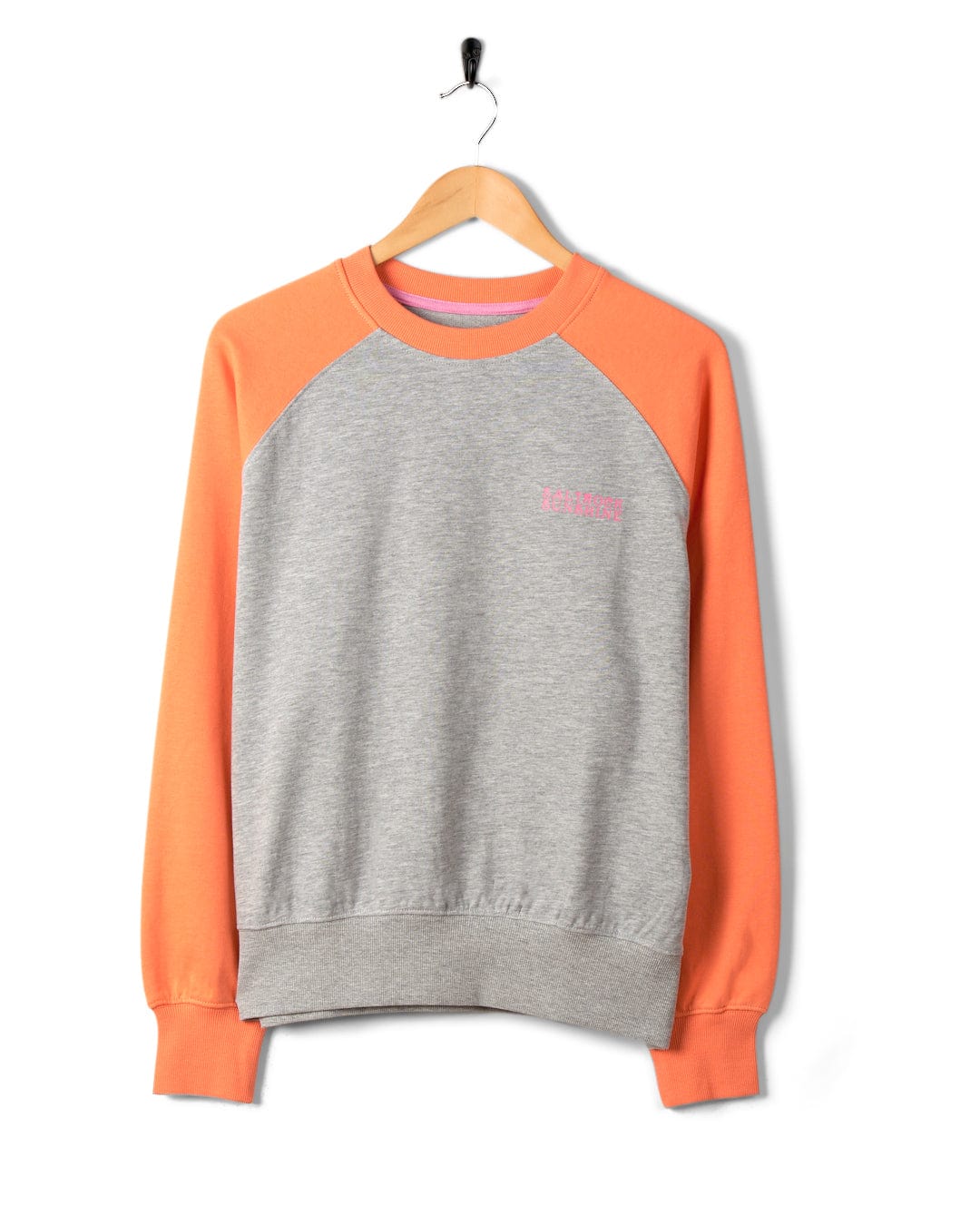 Gray and orange crew neck sweatshirt with raglan sleeves and the word "SALTROCK" embroidered in pink, hanging on a black hanger against a white background.