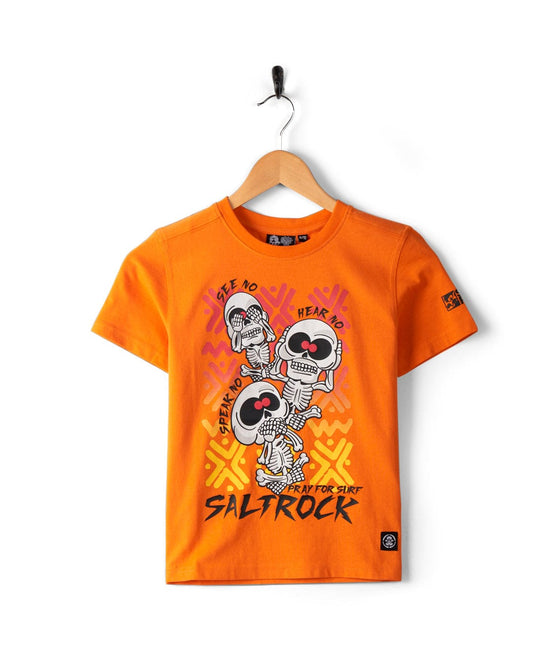 See No Skulls - Kids T-Shirt - Orange with graphic of three skeletons in "See No Evil, Hear No Evil, Speak No Evil" poses. Text reads "Saltrock" and "Pray for Surf." Crafted from 100% cotton for ultimate comfort with Saltrock branding.