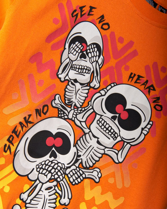 Illustration of three cartoon skeletons on an orange background, each depicting "see no evil," "hear no evil," and "speak no evil" gestures, perfect for adding a touch of fun to any collection. Featuring Saltrock branding and crafted from 100% cotton for ultimate comfort, the See No Skulls - Kids T-Shirt - Orange is a must-have.