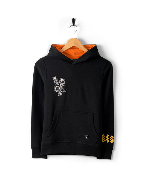 See No Skulls - Kids Recycled Pop Hoodie - Black, featuring a hood lined in orange, a small graphic on the front, and yellow arrow detail on the sleeve. It includes a kangaroo pocket for convenience and displays subtle Saltrock branding. The hoodie is hung on a wooden hanger against a white background.