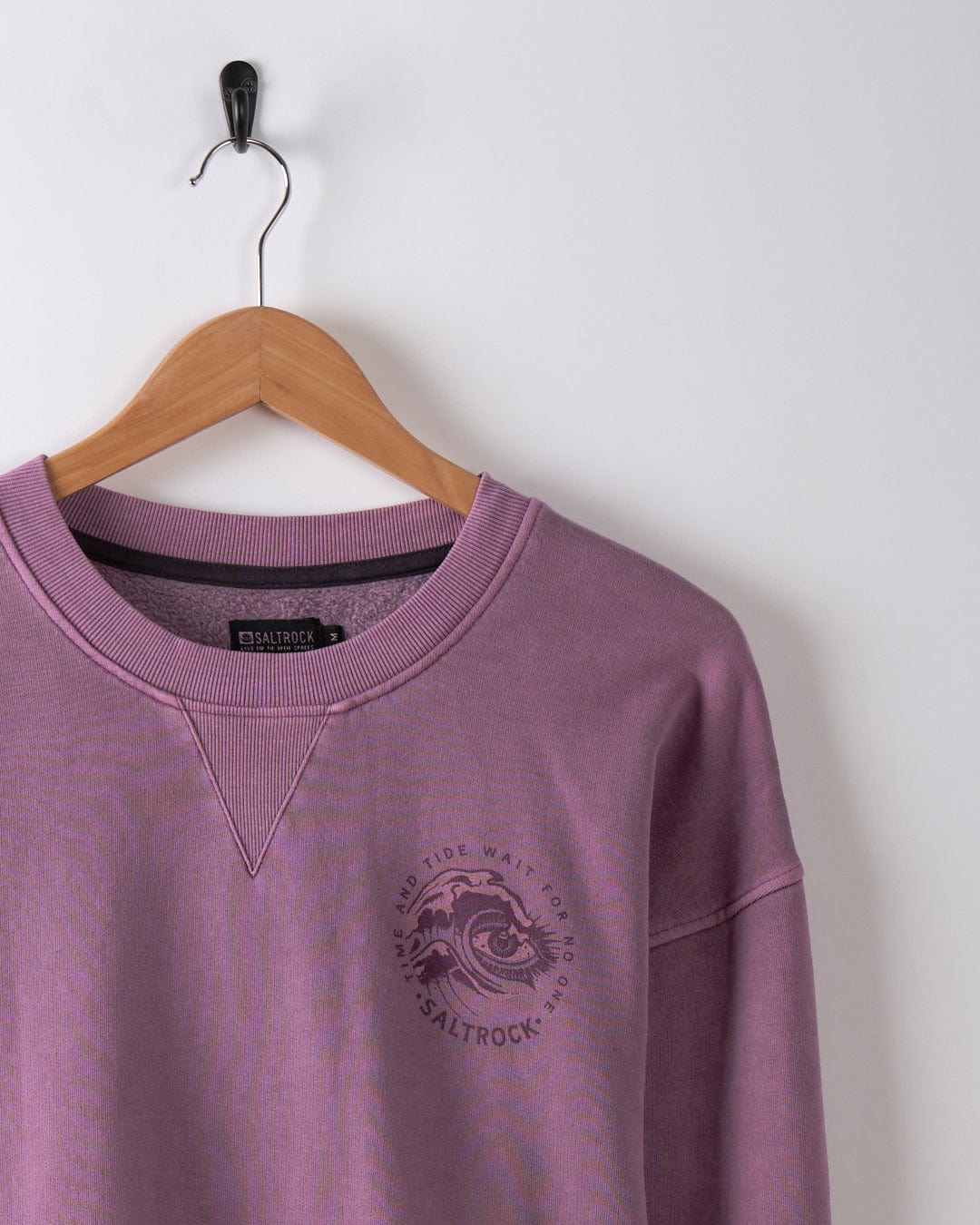 The Lunar 2 - Mens Oversized Sweat in Purple, by Saltrock, features a graphic on the chest and is displayed hanging on a wooden hanger against a white wall.