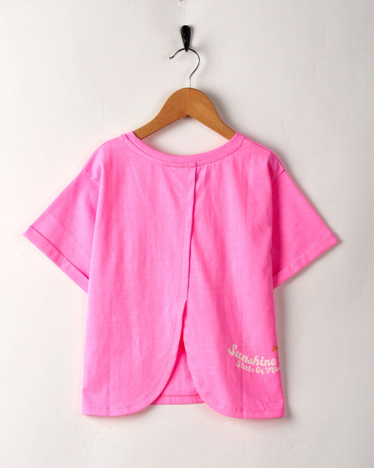Pink Sunshine State - Recycled Kids T-Shirt by Saltrock, featuring a crew neckline, hanging on a wooden hanger against a white wall.
