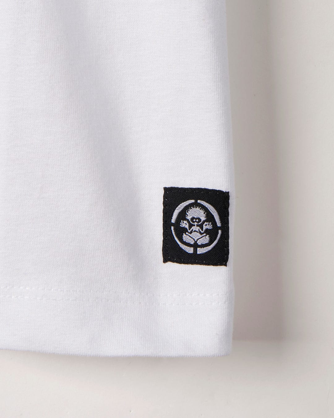 Close-up of a white sleeve featuring a small black patch with the Saltrock Taco Tok - Kids Short Sleeve T-Shirt logo.