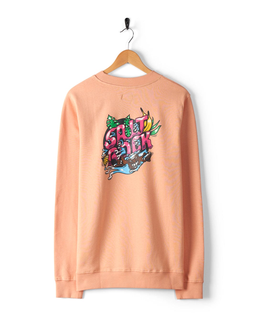 The Tahiti - Mens Sweat - Peach by Saltrock is a peach-colored sweatshirt displayed on a wooden hanger. It features distinctive Saltrock graphics with the word "Southpark" and various illustrated elements on the back. Made from 100% cotton, this oversized fit piece provides ultimate comfort and style.