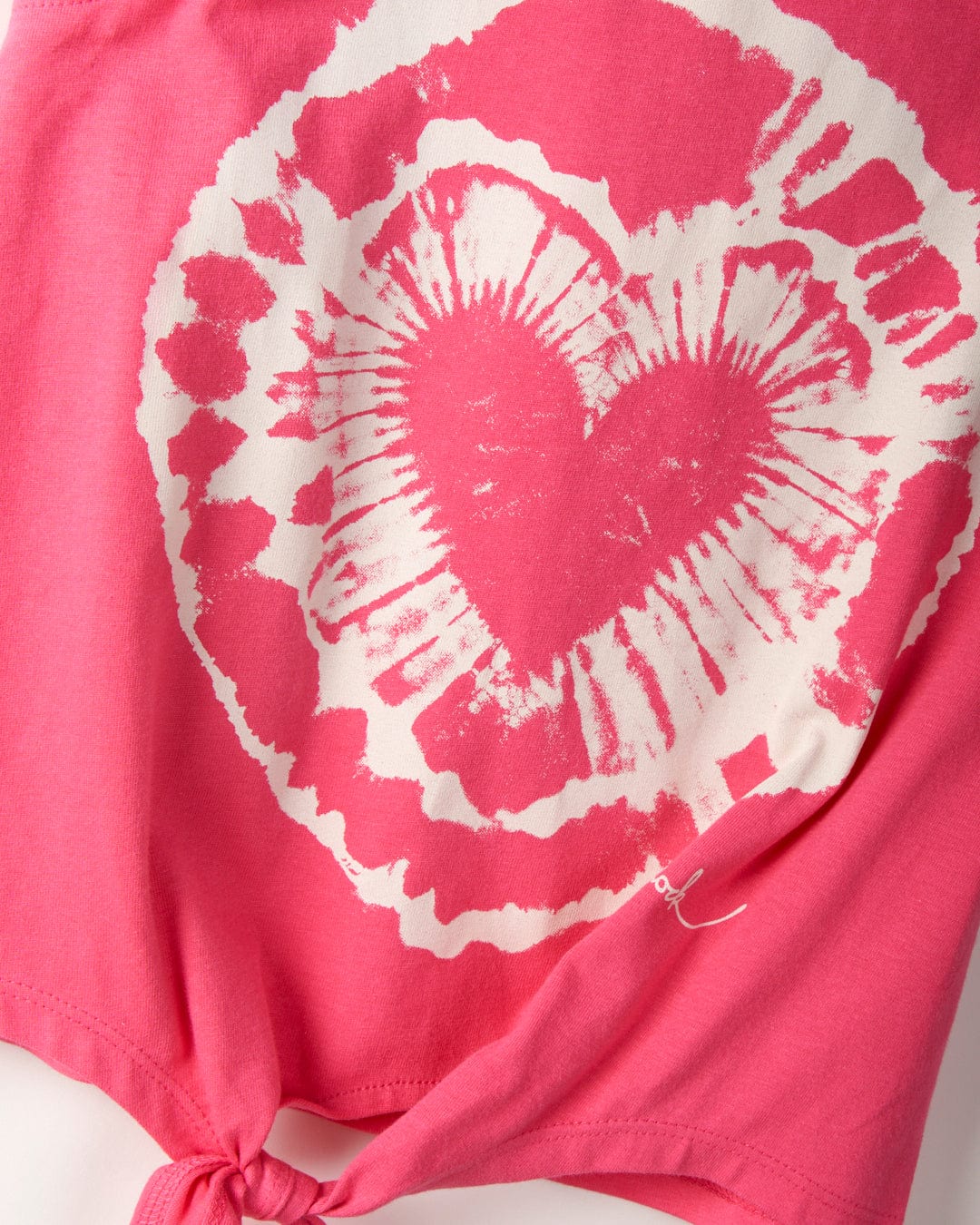 Close-up of a pink cotton Tie Dye Heart - Kids Tie Front Vest - Pink by Saltrock featuring a white circular pattern and a prominent heart shape in the center.
